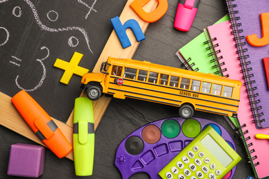Photo of Flat lay composition with yellow school bus model on black background. Transport for students