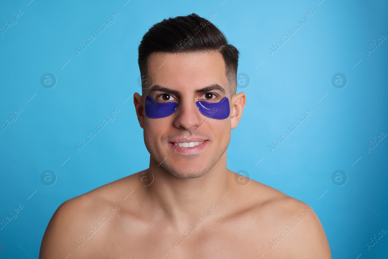 Photo of Man with under eye patches on light blue background