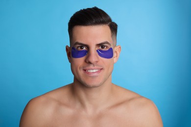 Photo of Man with under eye patches on light blue background