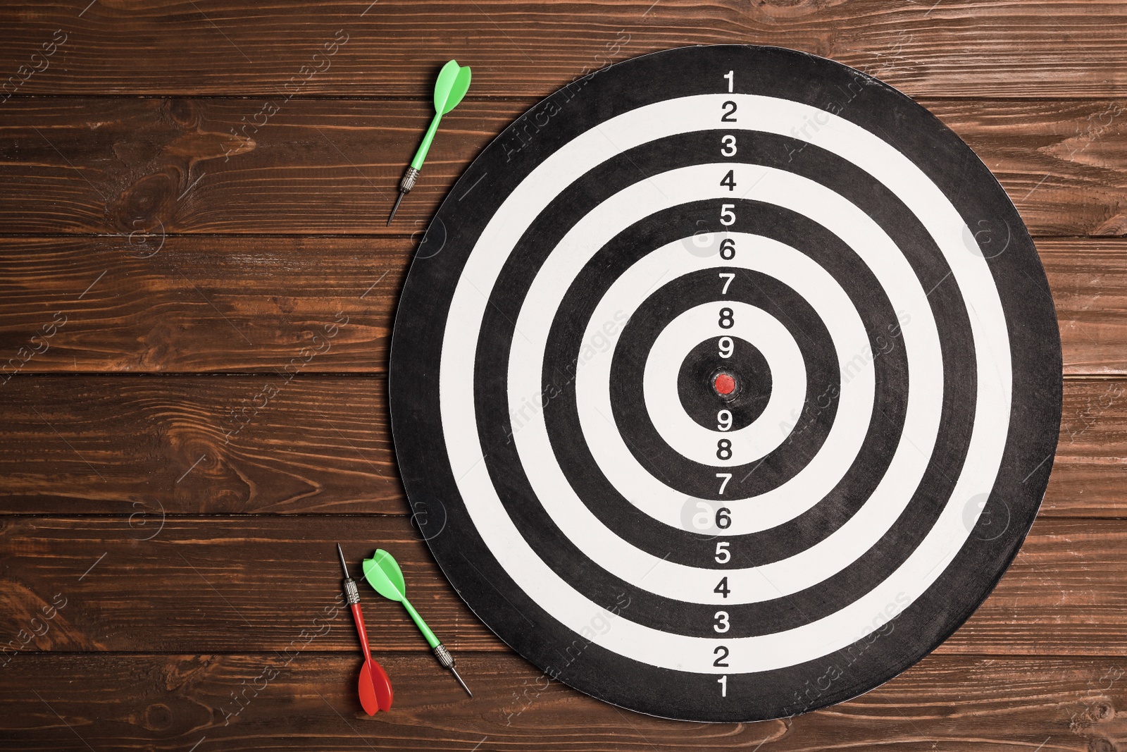 Photo of Dart board with color arrows on wooden background, top view. Space for text