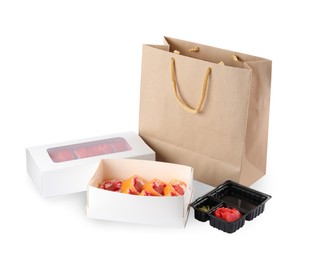 Photo of Food delivery. Boxes with delicious sushi rolls near paper package on white background
