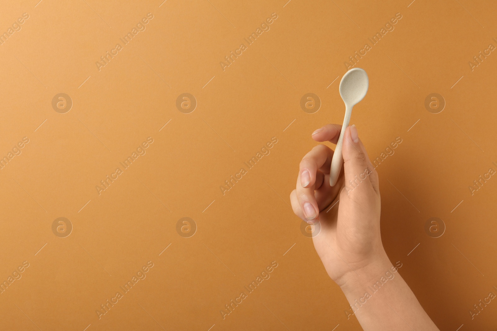 Photo of Woman holding empty small spoon on color background, closeup. Space for text