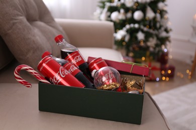 MYKOLAIV, UKRAINE - JANUARY 13, 2021: Coca-Cola bottles and cans, candy cane, Christmas decor in box indoors