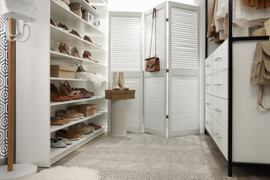 Photo of Dressing room interior with stylish shoes and accessories on shelves