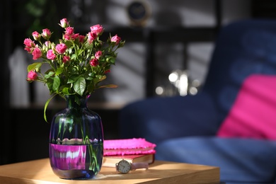 Photo of Glass vase with fresh flowers and wristwatch on wooden table. Space for text