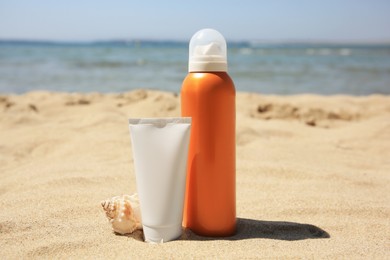 Sunscreens and seashell on sandy beach. Sun protection care