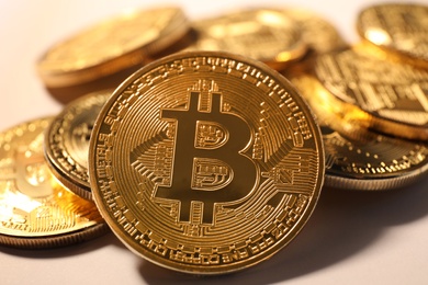 Photo of Shiny gold bitcoins on light background, closeup view. Digital currency