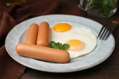 Photo of Delicious boiled sausages, fried eggs and parsley on wooden table, closeup