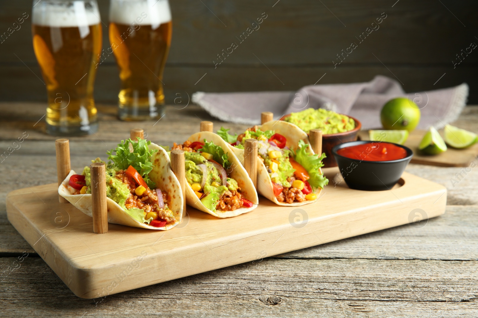 Photo of Delicious tacos with guacamole, meat and vegetables served on wooden table