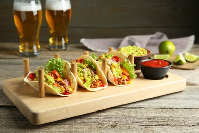 Photo of Delicious tacos with guacamole, meat and vegetables served on wooden table