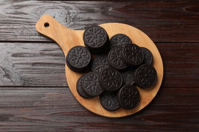 Photo of Board with tasty sandwich cookies on wooden table, top view