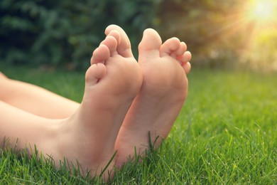 Photo of Teenage girl sitting barefoot on green grass outdoors, closeup