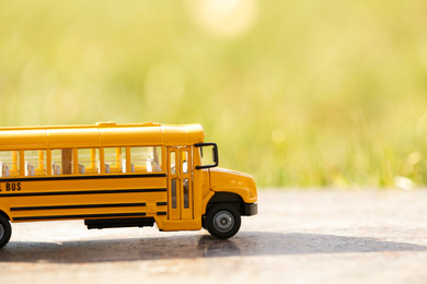 Photo of Yellow toy school bus outdoors on sunny day. Student's transport