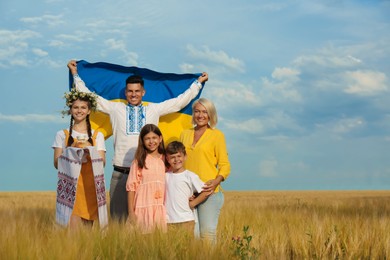 Happy family with national flag of Ukraine and treat in field. Space for text