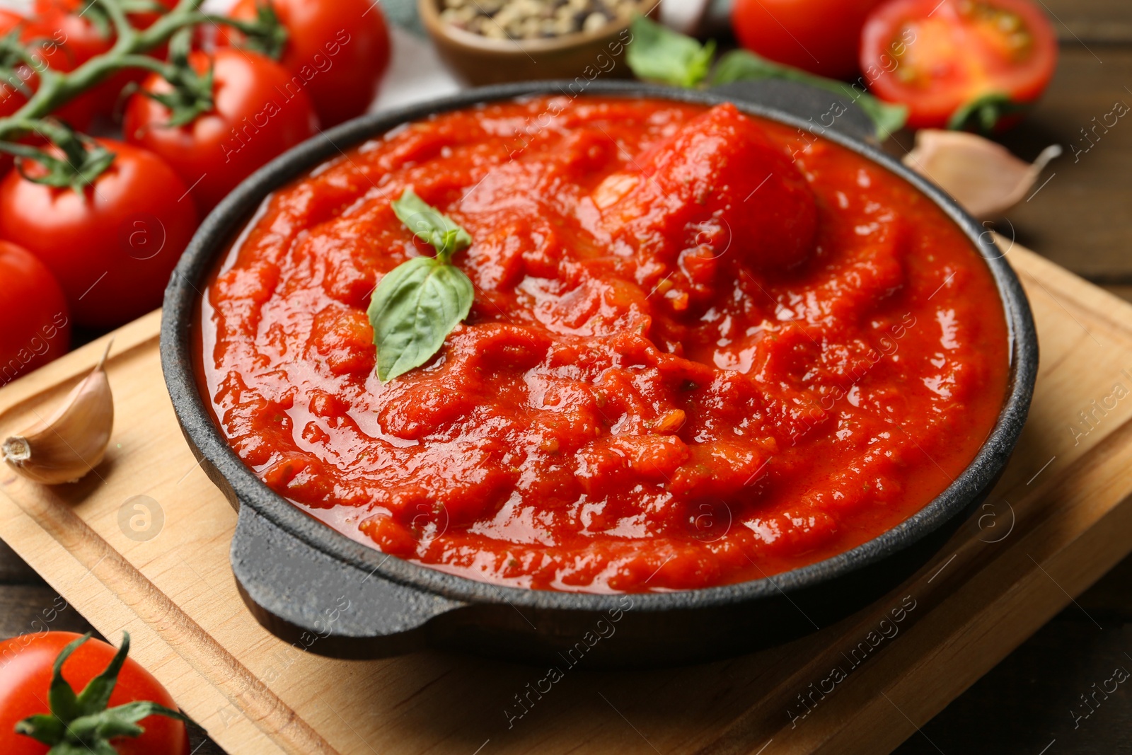 Photo of Homemade tomato sauce and basil in bowl on table, closeup