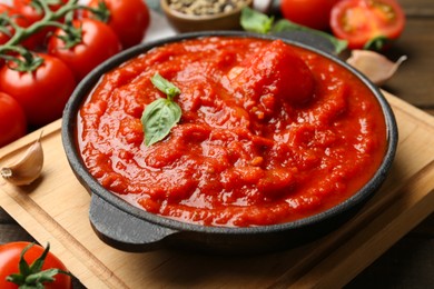 Photo of Homemade tomato sauce and basil in bowl on table, closeup