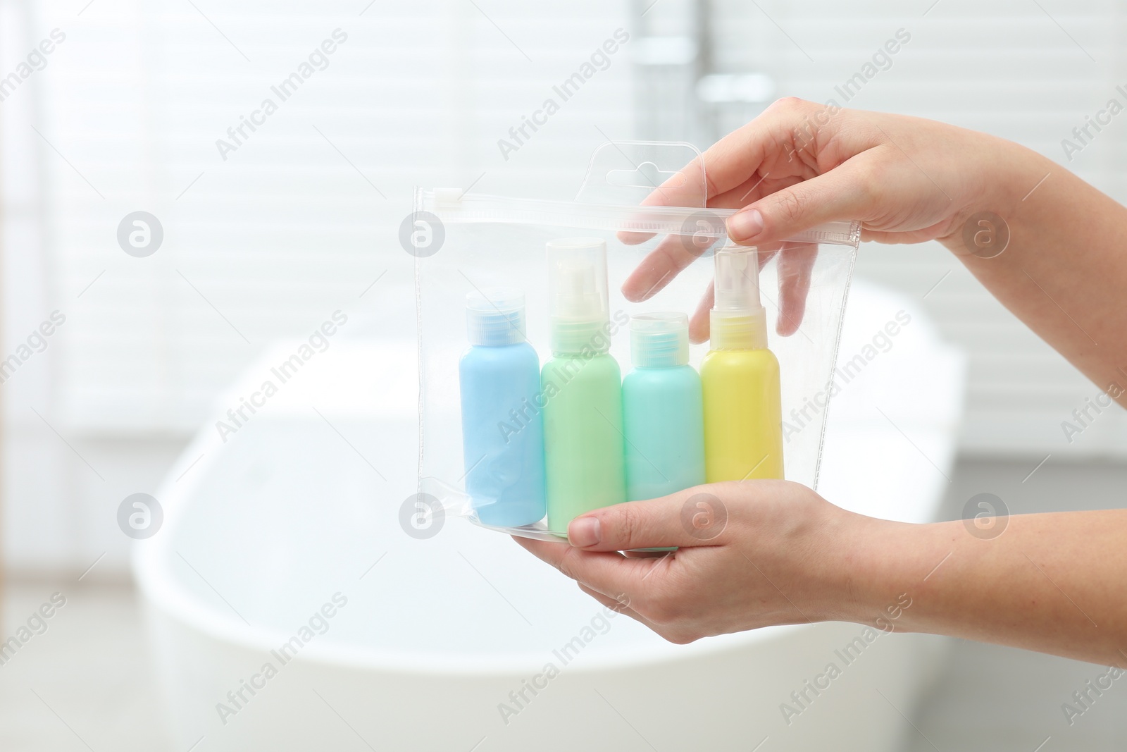 Photo of Woman with plastic bag of cosmetic travel kit in bathroom, closeup and space for text. Bath accessories