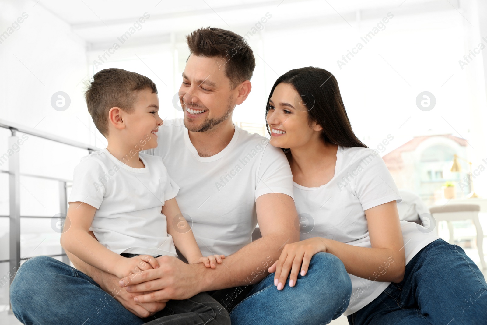 Photo of Happy parents and their son sitting together on floor at home. Family time