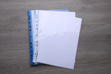 File folder with punched pockets and paper sheets on wooden table, top view