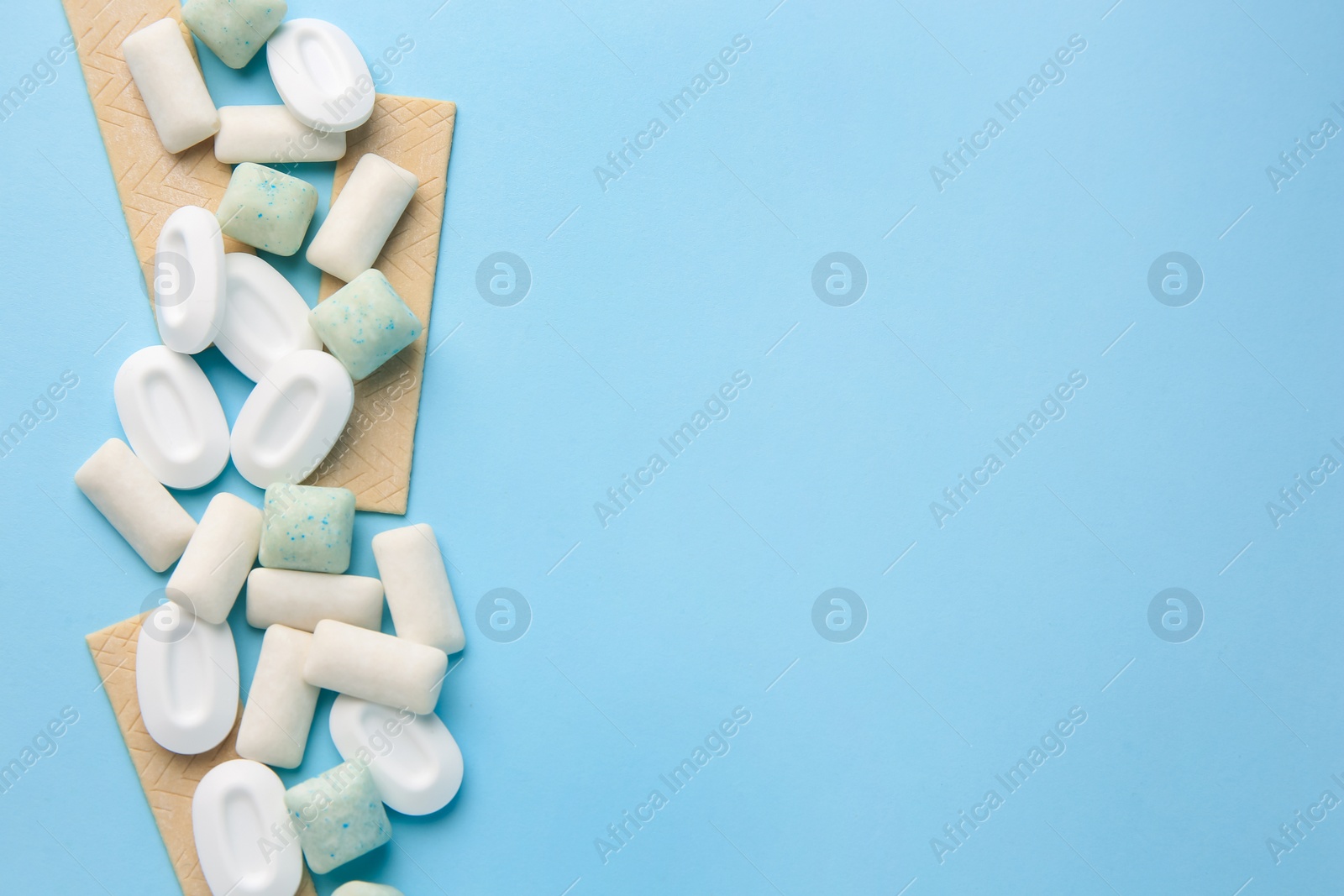 Photo of Many different chewing gums on light blue background, flat lay. Space for text