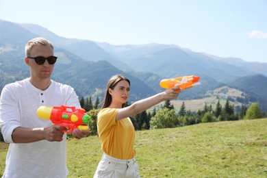 Happy couple with water guns having fun in mountains