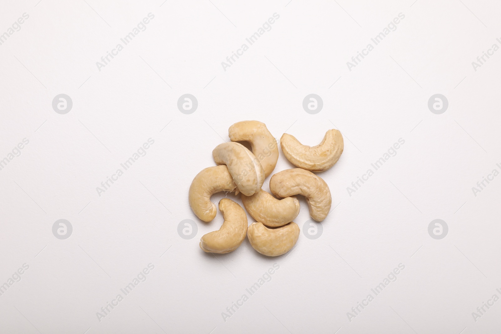 Photo of Many tasty cashew nuts on white background, top view