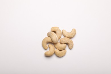 Photo of Many tasty cashew nuts on white background, top view