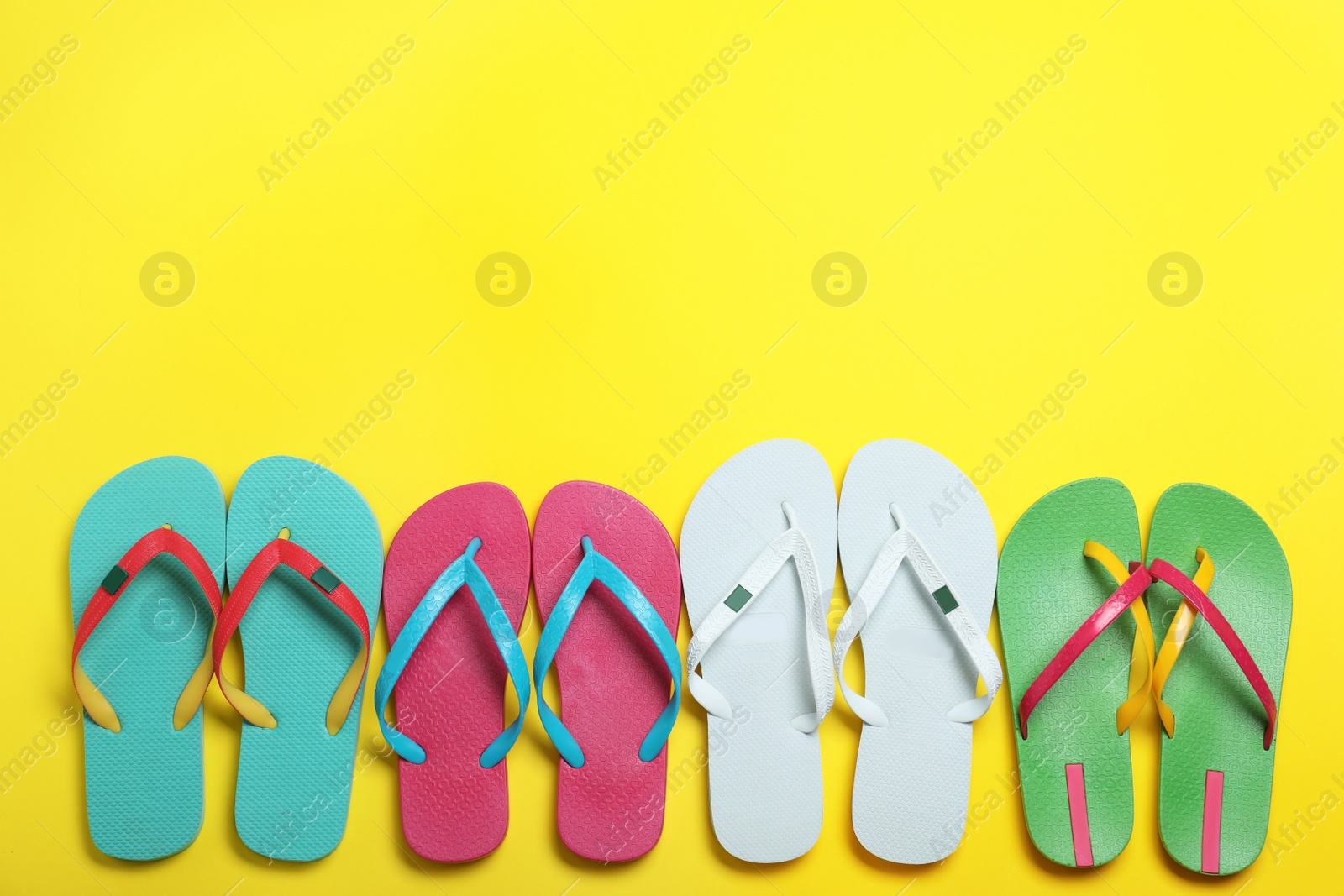 Photo of Many different stylish flip flops on yellow background, flat lay. Space for text