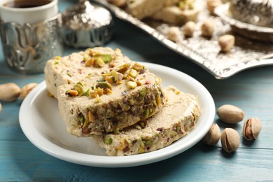Photo of Tasty halva with pistachios on light blue wooden table, closeup