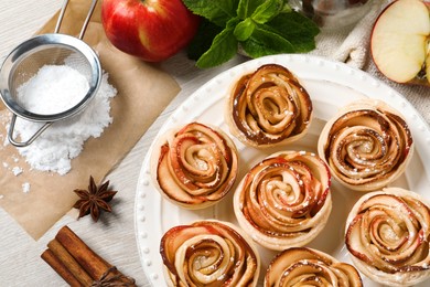 Photo of Freshly baked apple roses on white wooden table, flat lay. Beautiful dessert