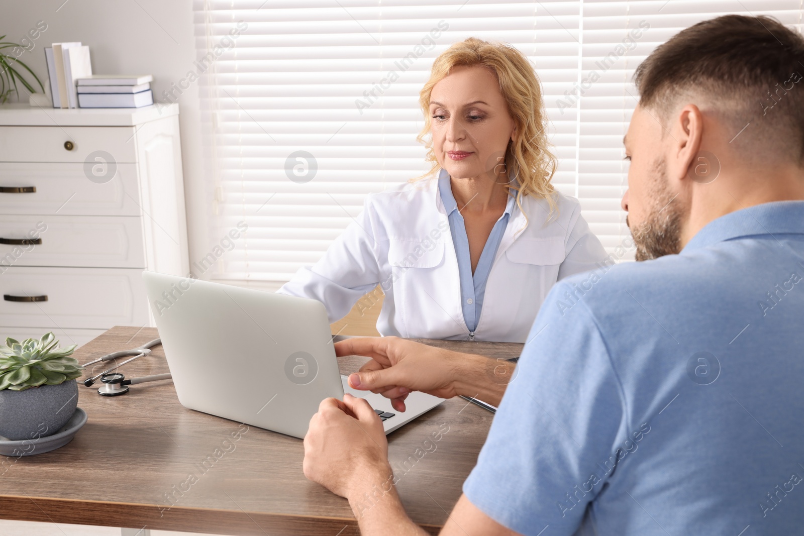 Photo of Doctor consulting patient at table in clinic