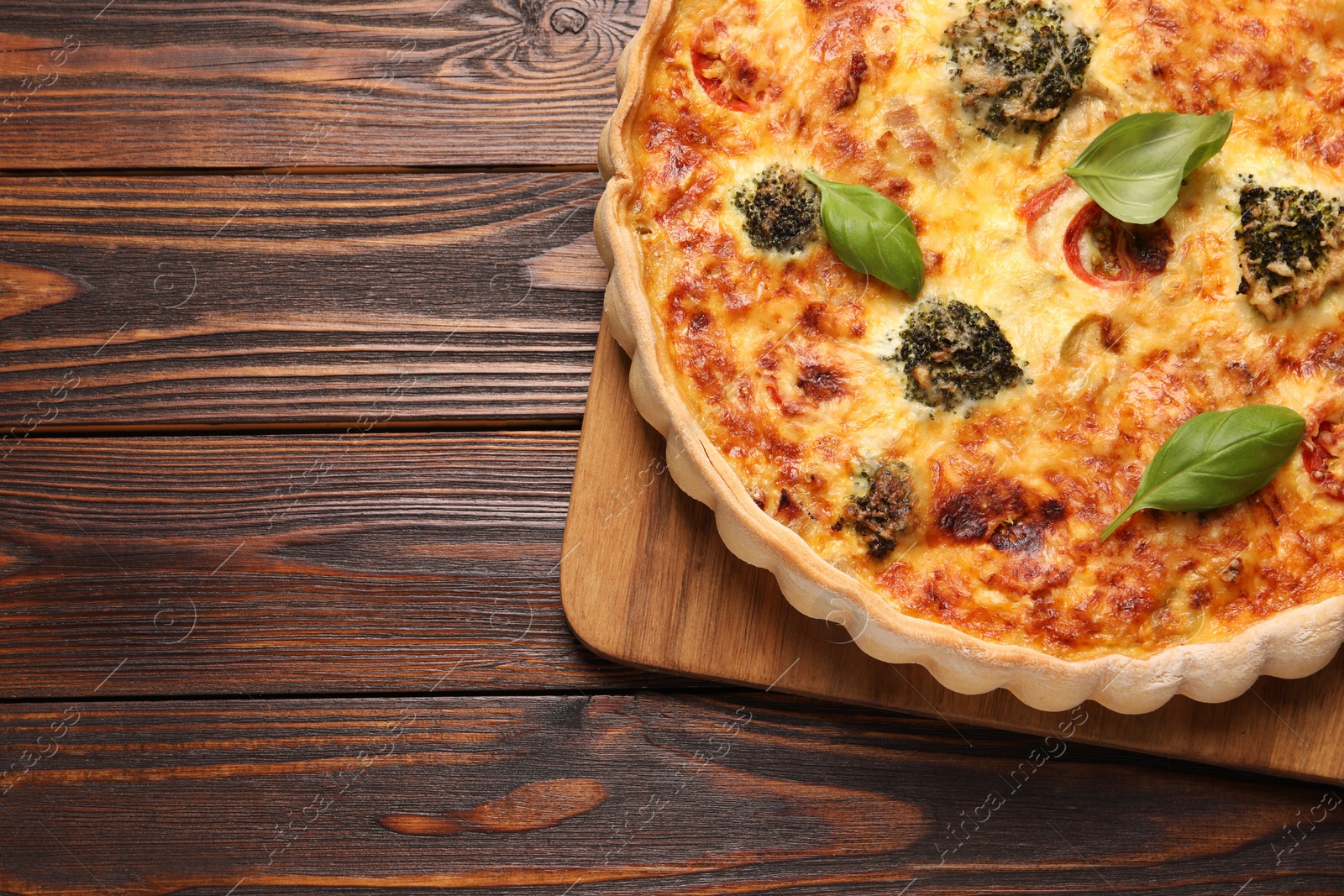 Photo of Delicious homemade vegetable quiche on wooden table, top view. Space for text