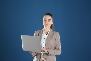 Photo of Portrait of young woman in office wear with laptop on color background