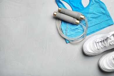 Photo of Flat lay composition with jump rope, gym equipment and space for text on grey background