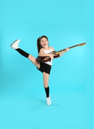 Cute little girl playing guitar on color background