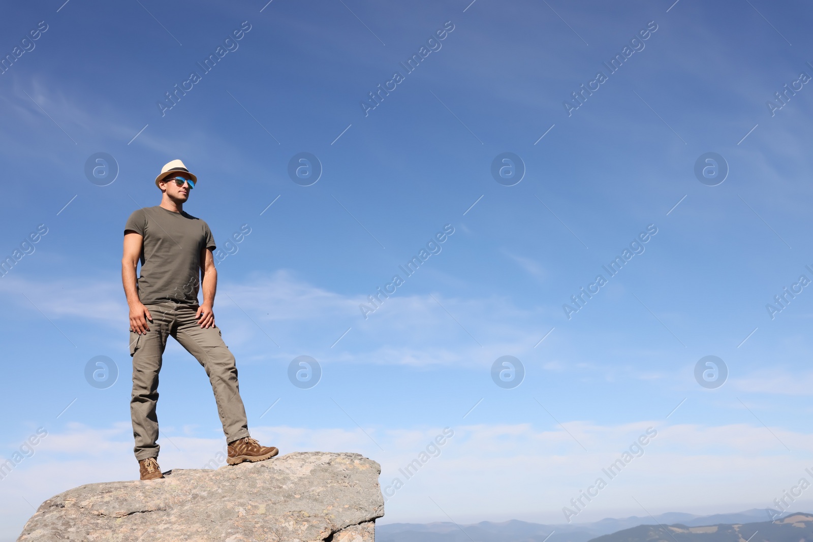 Photo of Man enjoying picturesque view on cliff in mountains. Space for text