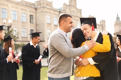 Photo of Happy student with parents after graduation ceremony outdoors