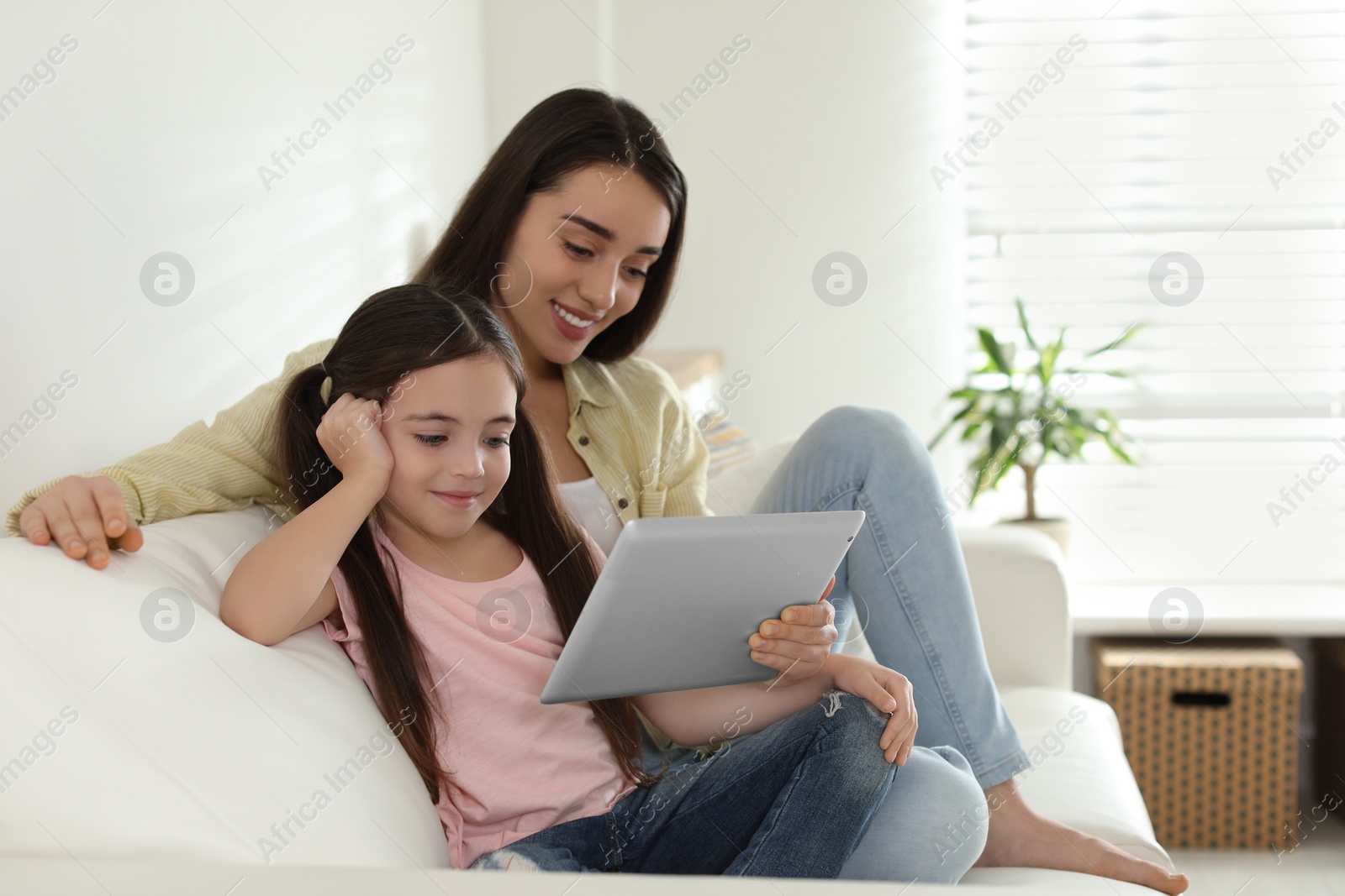 Photo of Mother and daughter reading E-book together at home