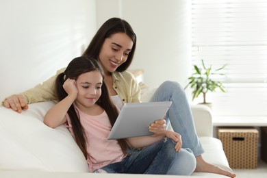 Mother and daughter reading E-book together at home