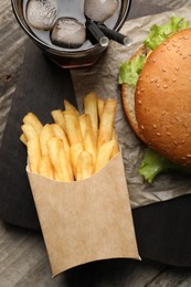 Photo of French fries, tasty burger and drink on wooden table, flat lay
