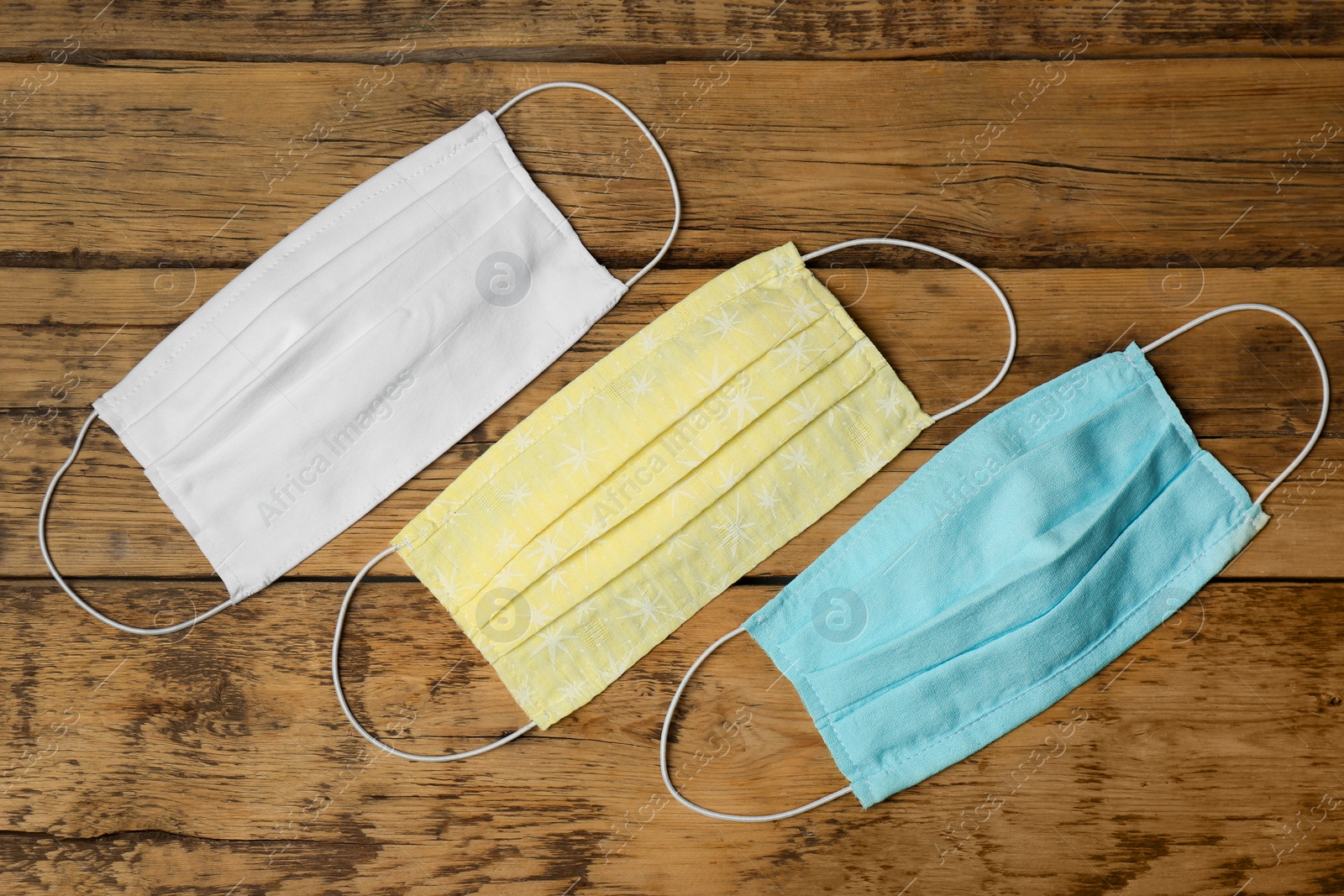 Photo of Homemade protective face masks on wooden table, flat lay