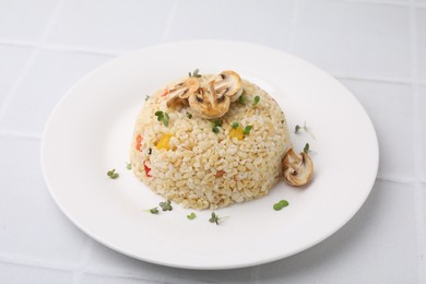 Delicious bulgur with vegetables, mushrooms and microgreens on white table, closeup