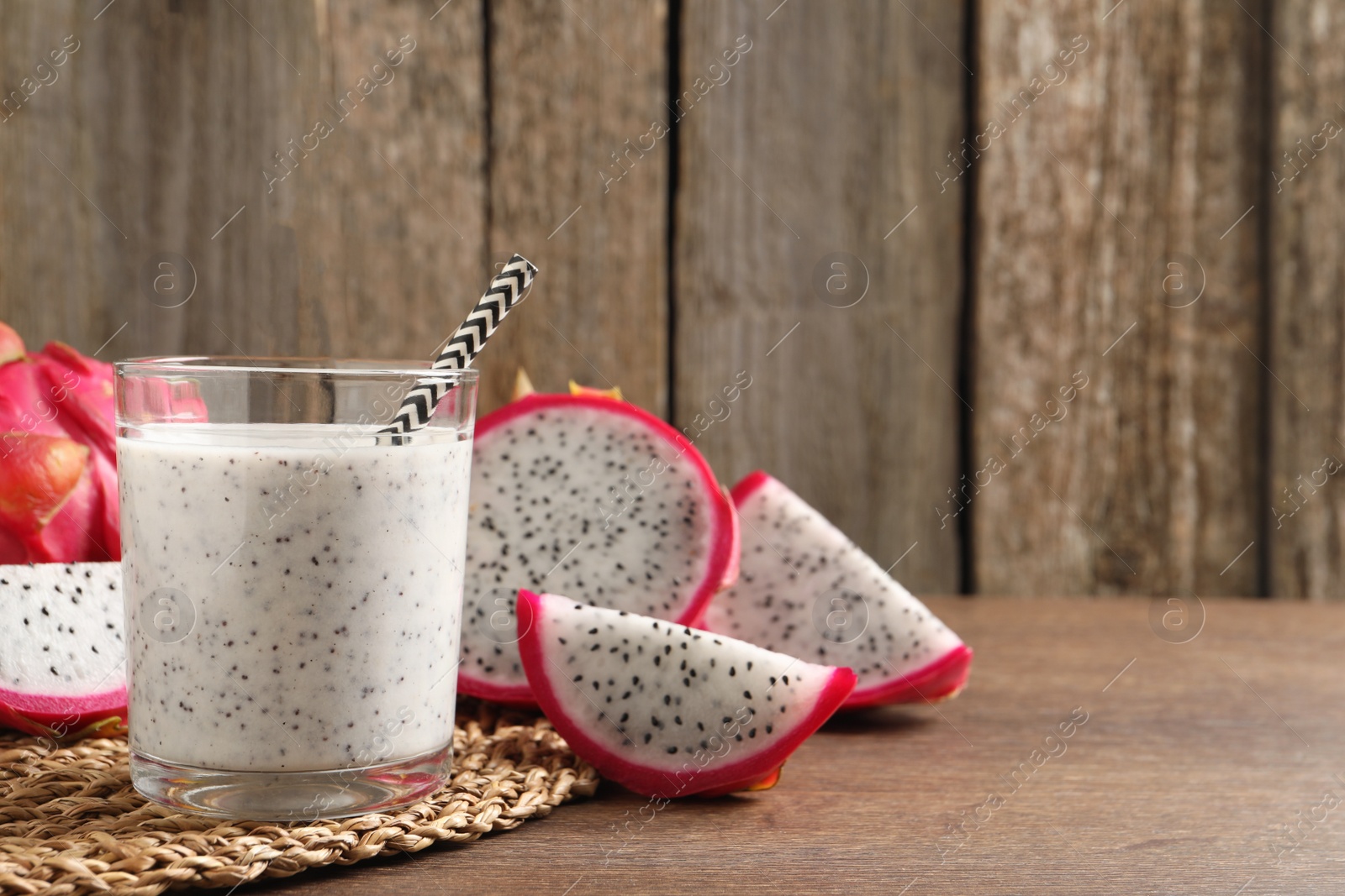 Photo of Delicious pitahaya smoothie and fresh fruits on wooden table, space for text