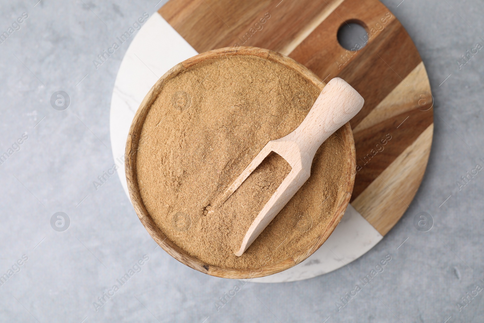 Photo of Dietary fiber. Psyllium husk powder in bowl and scoop on grey table, top view