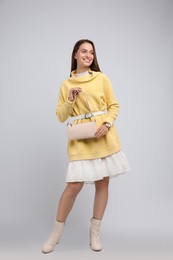 Photo of Fashionable young woman with stylish bag on light background