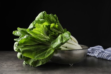 Photo of Fresh green pak choy cabbages with water drops in sieve on grey table