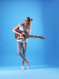 Photo of Young woman playing electric guitar on color background