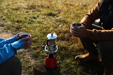 Photo of Young couple drinking coffee near camping tents outdoors, closeup
