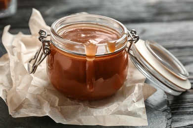 Jar with tasty caramel sauce on table