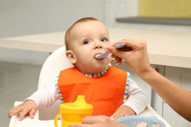 Young mother feeding her little baby at home